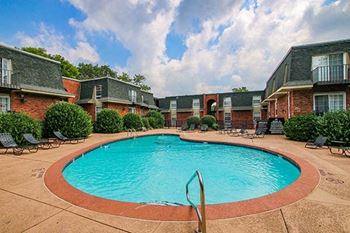 a swimming pool with chaise lounge chairs in front of a building